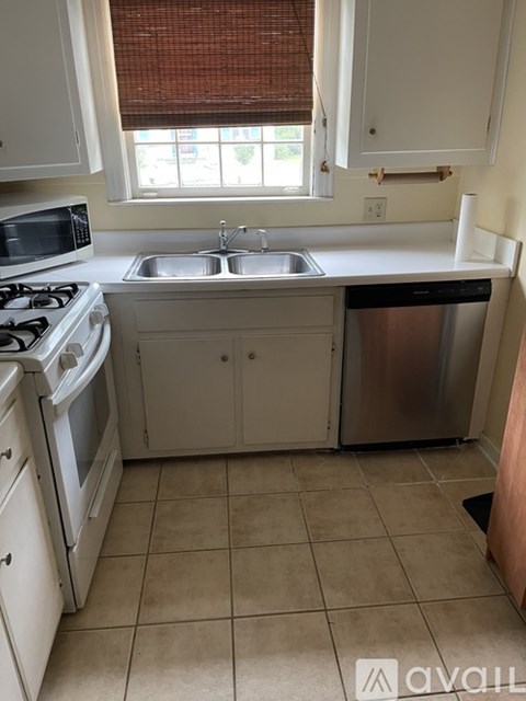 A kitchen with white cabinets and a tiled floor.