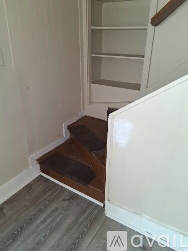A white cabinet with a wooden handle is in a room with white walls.