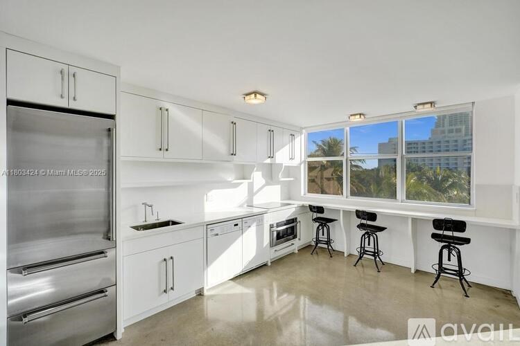 A kitchen with white cabinets and a stainless steel refrigerator.