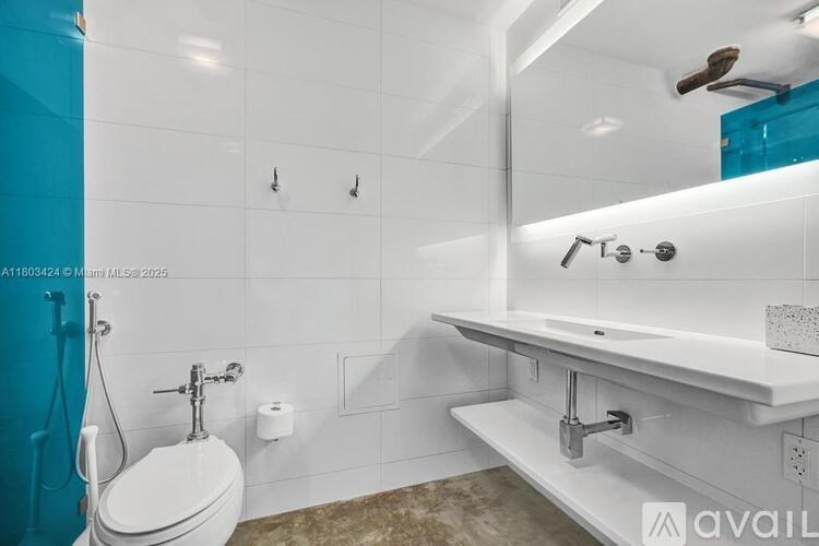A white toilet is in a bathroom with a white sink and a blue shower curtain.
