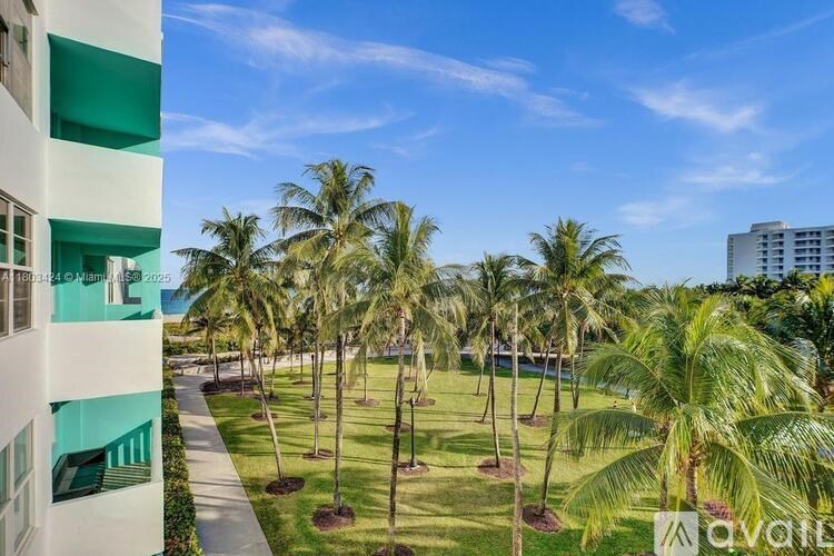 A view of a palm tree lined lawn from a balcony.