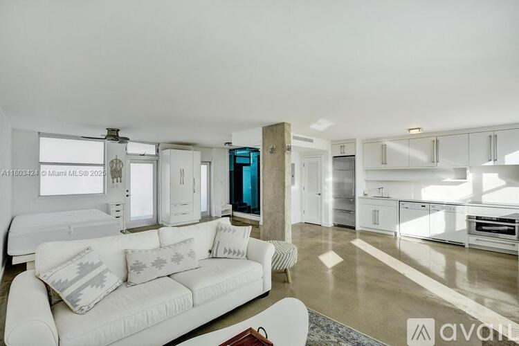 A modern living room with a white sofa and a kitchen in the background.