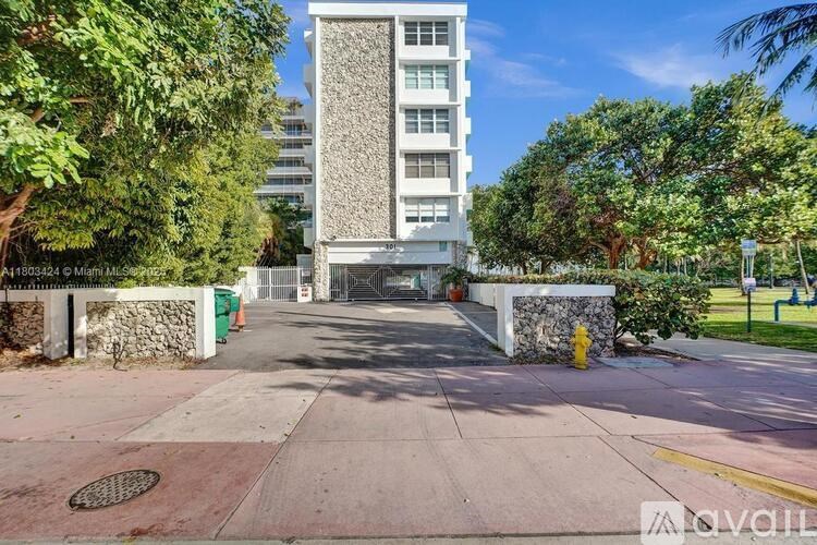 A tall building with a white facade stands between two trees.
