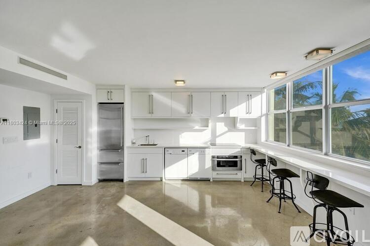 A kitchen with white cabinets and a refrigerator.