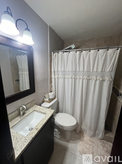 A bathroom with a sink, toilet, and shower curtain.