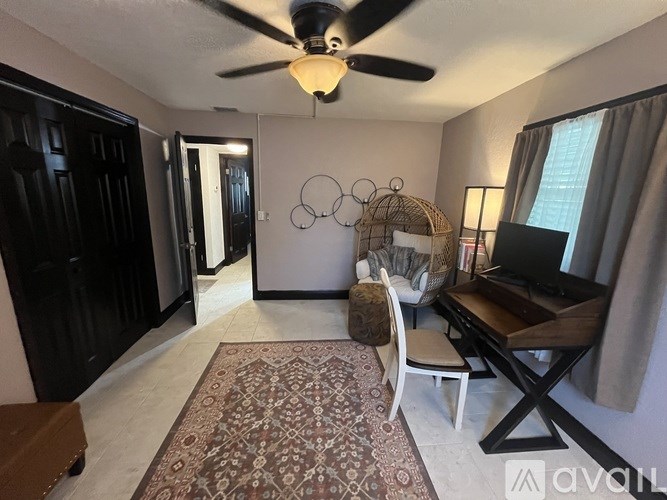 A living room with a ceiling fan and a rug on the floor.