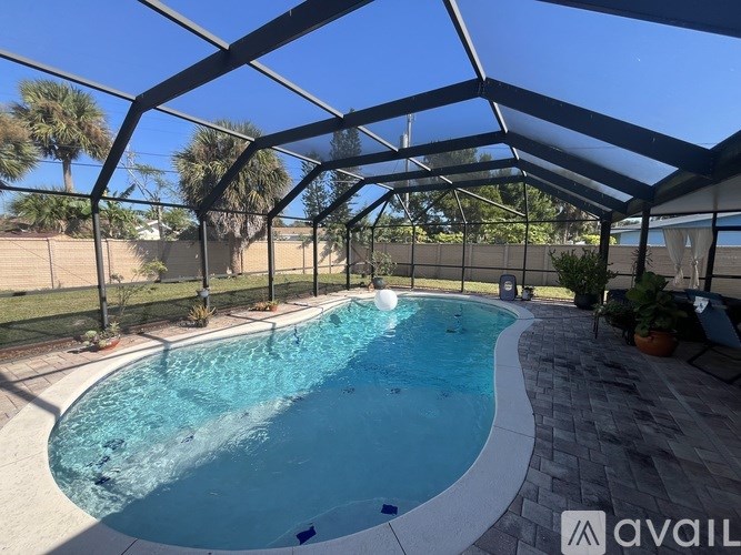 A pool under a glass roof with trees in the background.