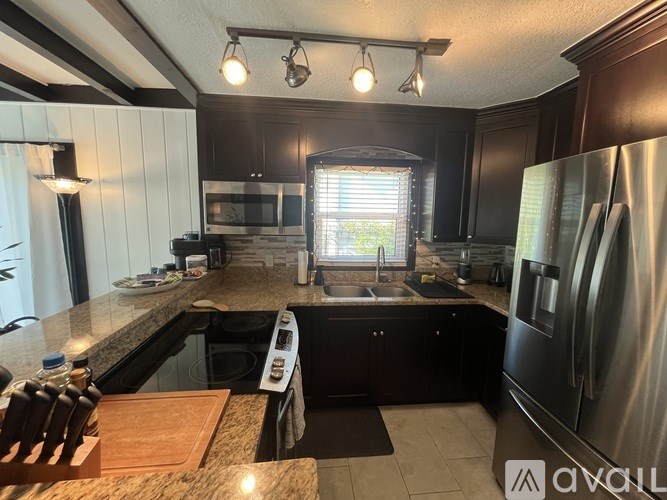 A kitchen with a black refrigerator and a black oven.