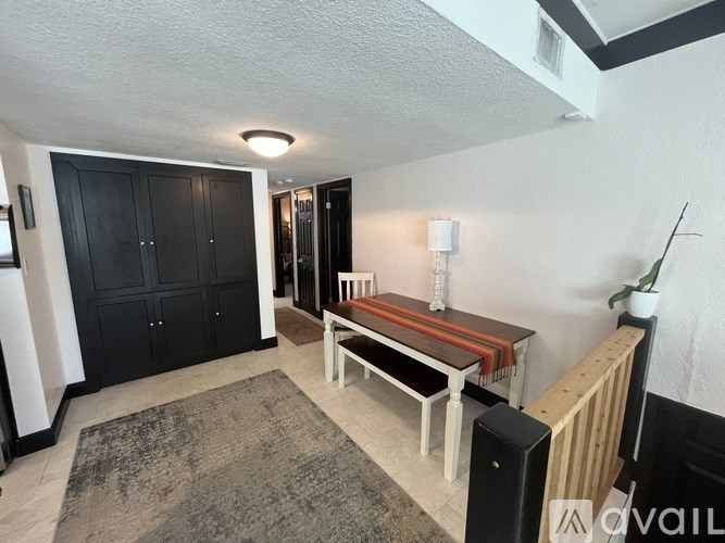 A room with a bench, a rug, and a black door.