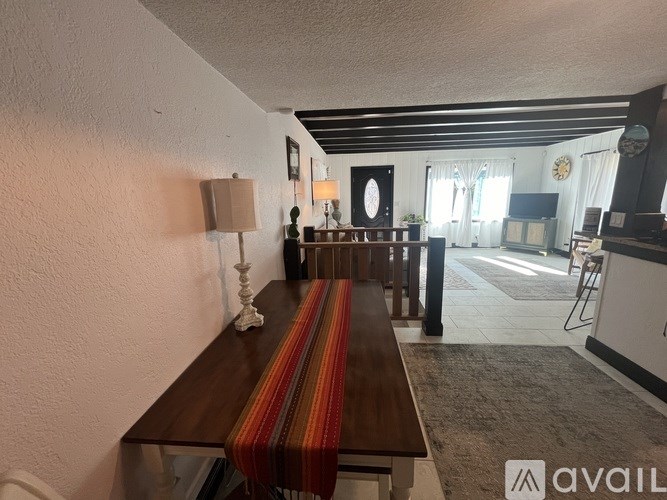 A long wooden table with a striped runner is in the middle of a room.