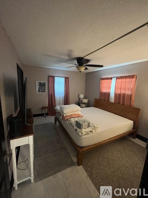 A bedroom with a bed, a television, and a ceiling fan.