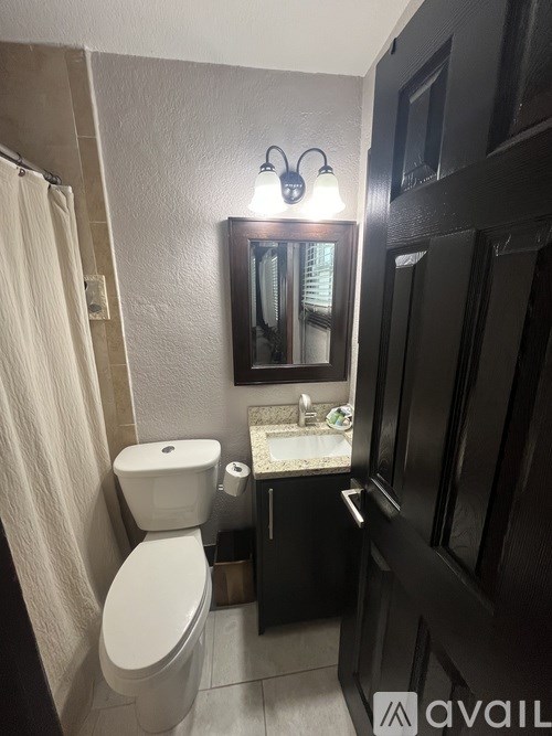 A bathroom with a toilet, sink, and mirror.