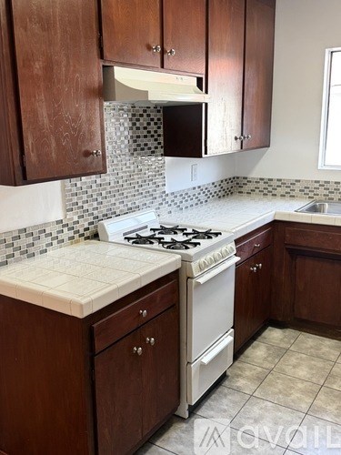 A kitchen with a white stove and brown cabinets.