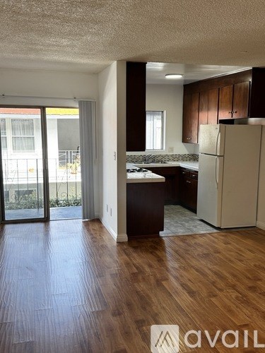 A kitchen with wooden floors and a refrigerator.