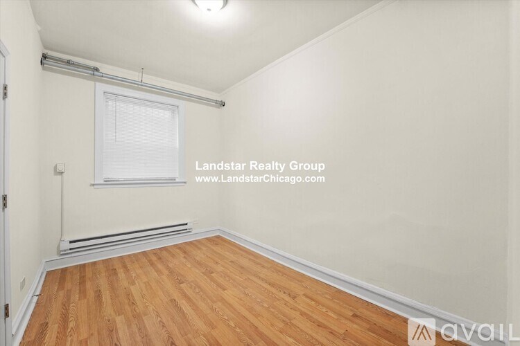 A room with wooden flooring and a window with blinds.