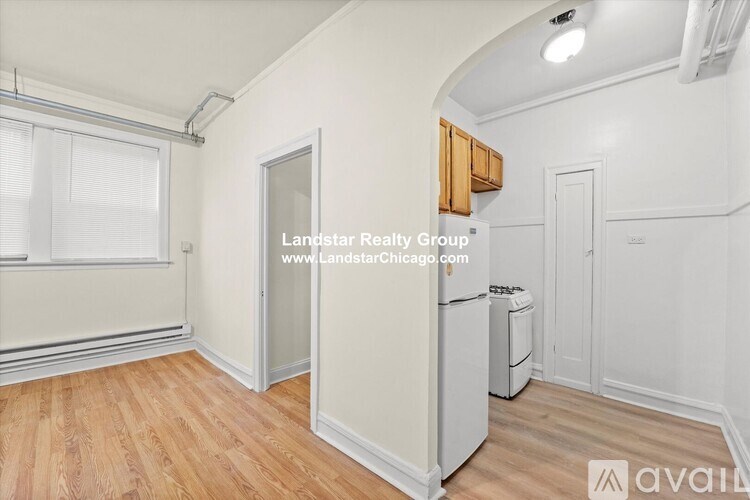 A room with wooden floors and white walls, with a window on the left and a door on the right.