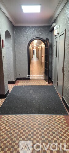 A hallway with a black mat on the floor and a tiled floor.