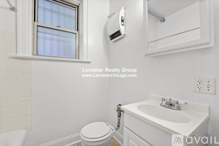 A white bathroom with a toilet, sink, and window.