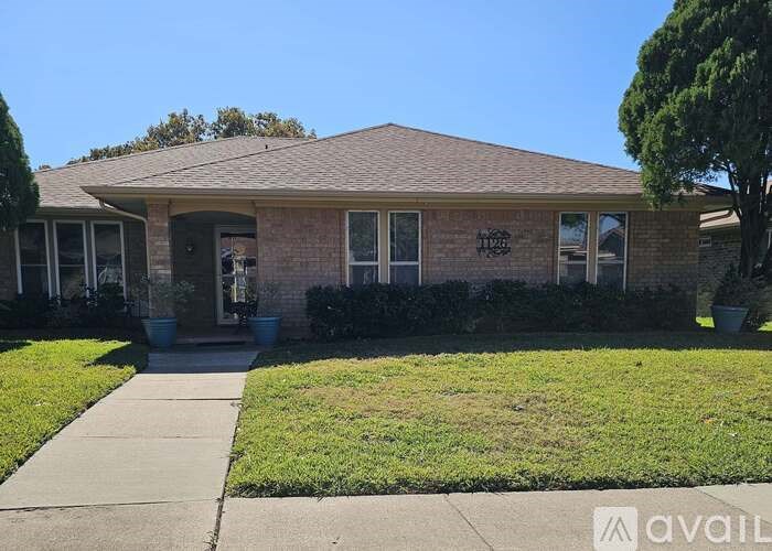 A house with a brown roof and a front yard with a sidewalk.