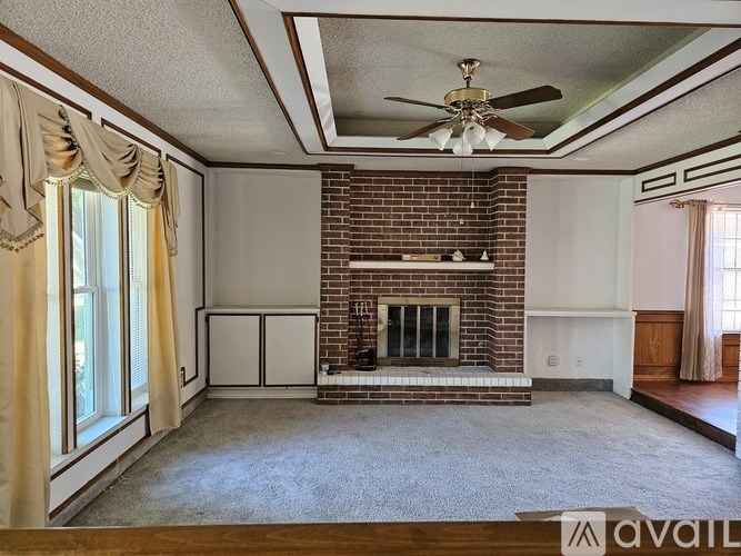 A living room with a fireplace and a ceiling fan.