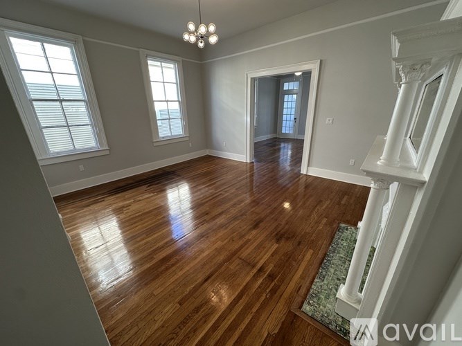 A spacious room with wooden floors and white walls.