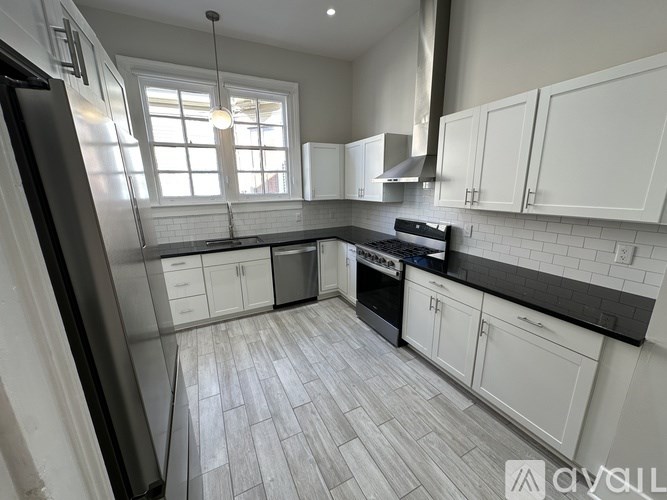 A modern kitchen with white cabinets and a black countertop.