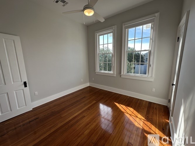 A room with a ceiling fan and two windows.