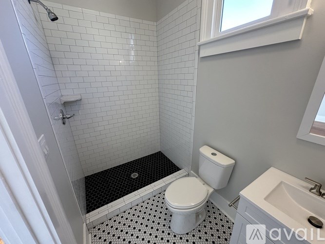 A white toilet sits in a bathroom with a black and white tile floor.