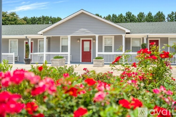 A house with a red door is surrounded by red flowers.
