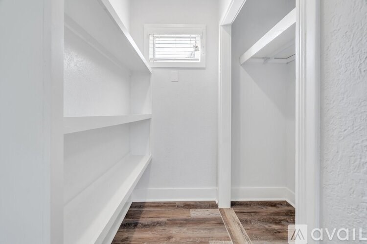 A hallway with white walls and wooden flooring.