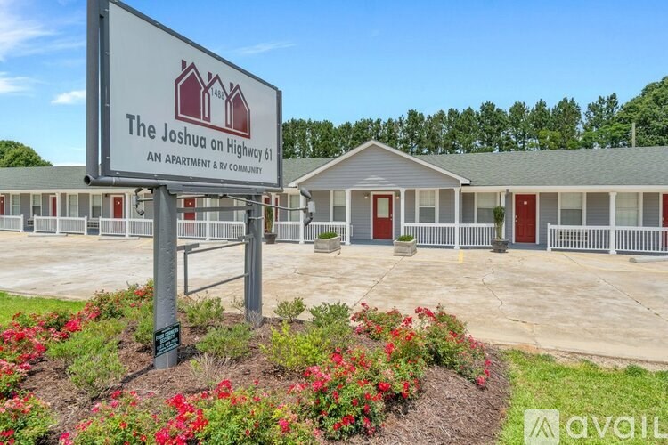 A sign for The Joshua apartment and community is in front of a building.