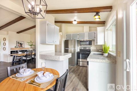 A modern kitchen with a wooden table set for two.