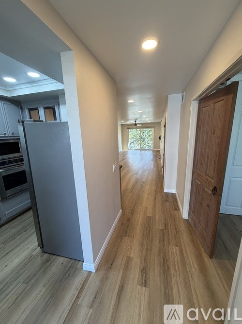 A long hallway with a wooden floor and a door on the right.