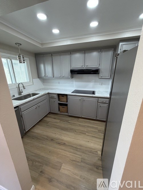 A kitchen with wooden floors and white cabinets.