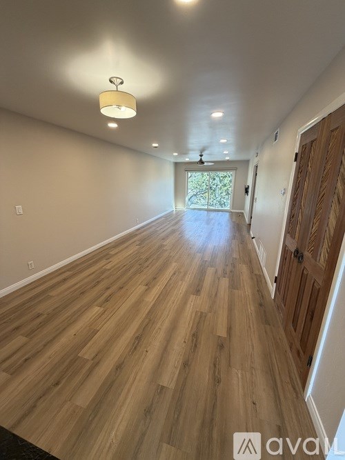 A long hallway with wooden floors and a ceiling fan.