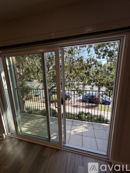 A sliding glass door with a view of a street and cars.