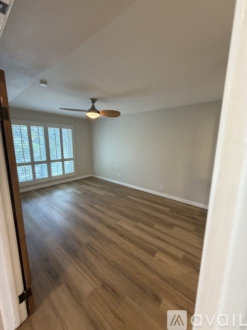 A room with wooden flooring and a ceiling fan.