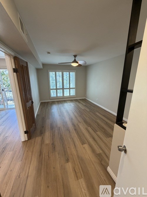 A room with wooden flooring and a ceiling fan.
