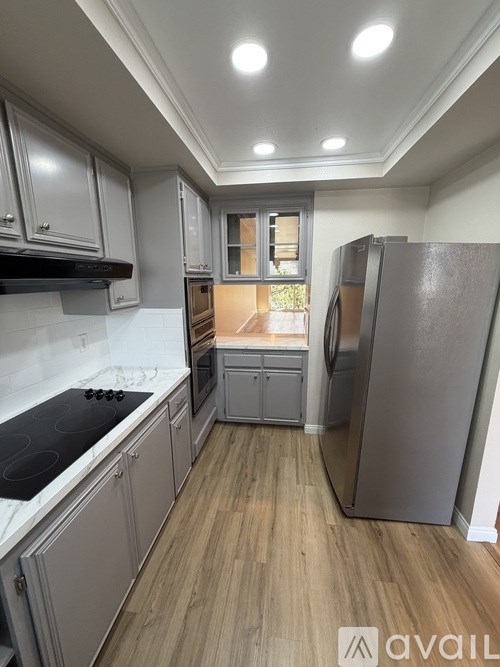 A kitchen with a refrigerator, stove, and cabinets.