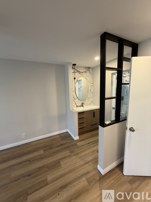 A bathroom with a mirror and wooden floors.