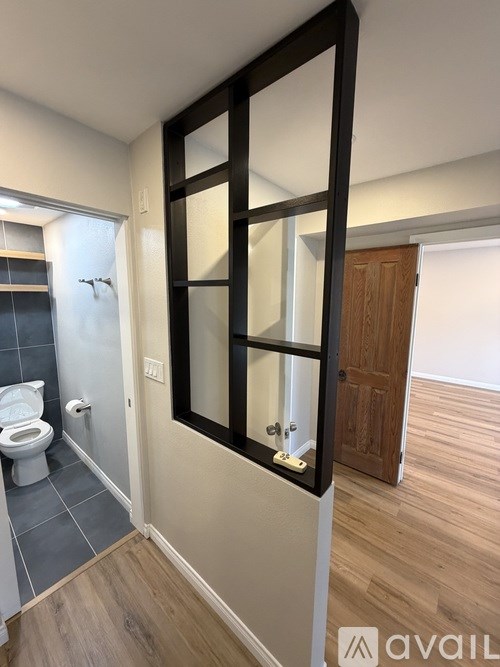 A bathroom with a toilet, a mirror, and a wooden door.