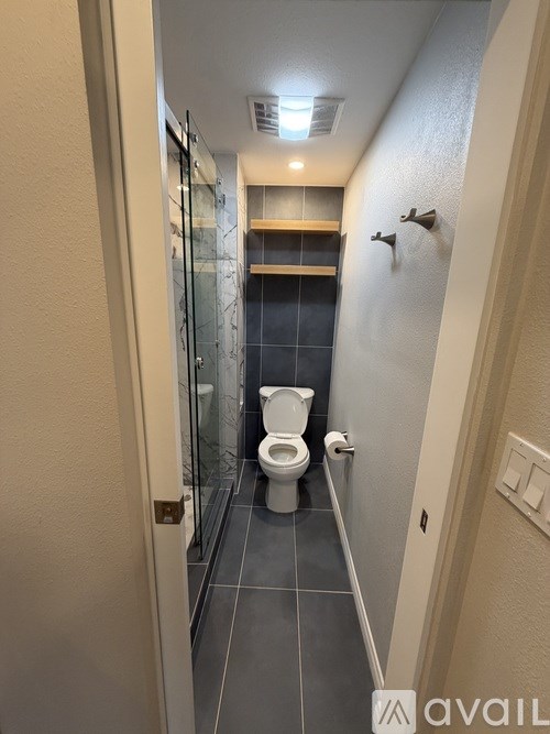 A bathroom with a toilet and a glass shower door.
