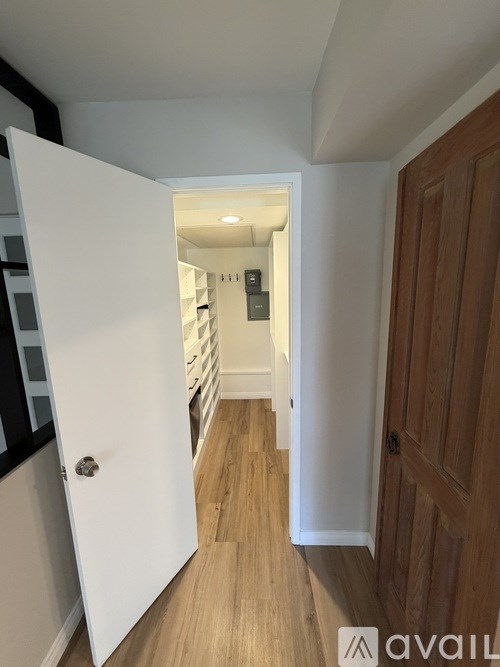 A hallway with a white door and wooden floors.