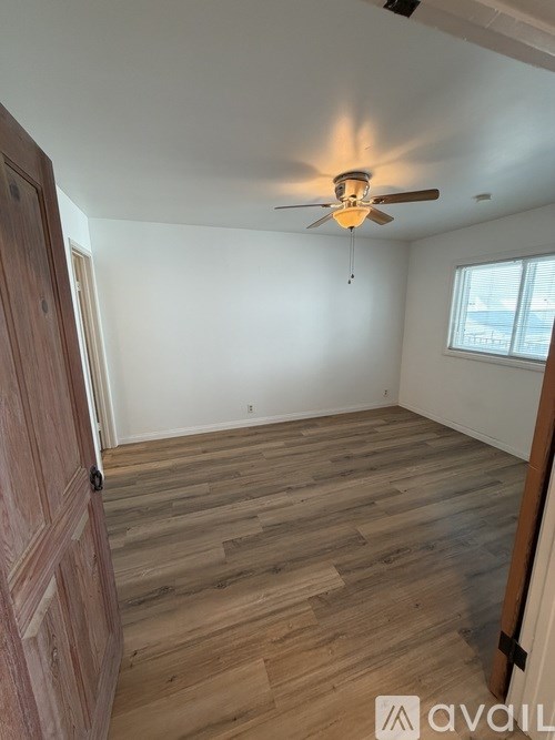 A room with wooden flooring and a ceiling fan.