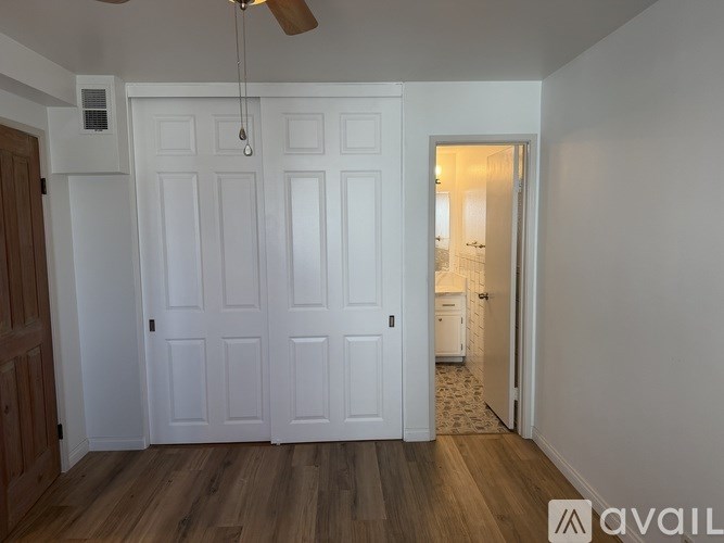 A room with a ceiling fan and a door leading to another room.