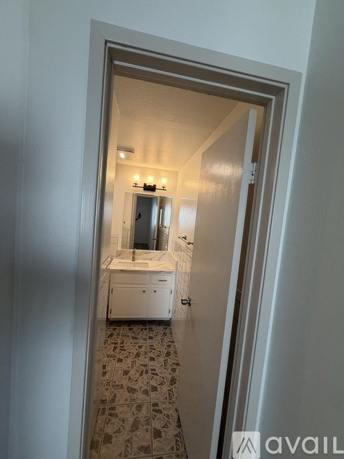 A bathroom with a sink, mirror, and tiled floor is visible through an open door.