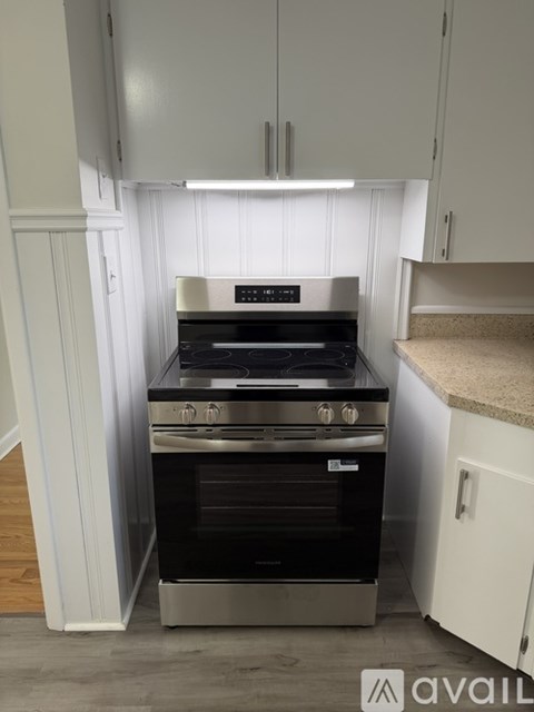 A modern kitchen with a stainless steel oven and white cabinets.