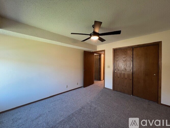 A room with a ceiling fan and carpeted floor.