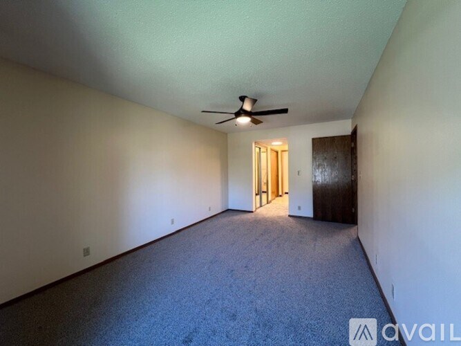 A room with a carpeted floor and a ceiling fan.