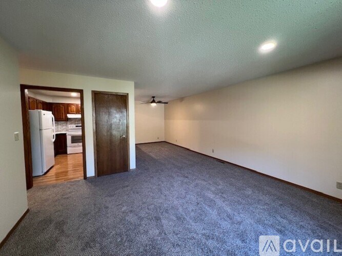 A room with a carpeted floor and a ceiling fan.